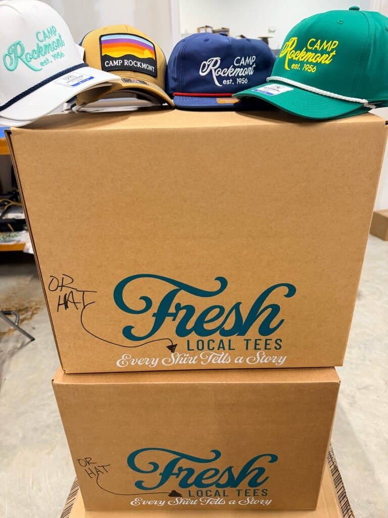 Custom Camp Rockmont hats on Fresh Local Tees boxes